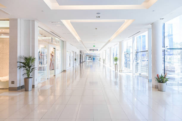 A woman in a red dress walks near tall buildings and shops in a bustling retail and commercial area.