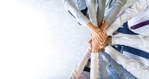 A group of people placing their hands together in a show of unity and teamwork.